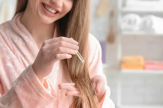 Smiling girl joyfully applying a hair care drop to her strands with a happy expression, showcasing the process of enhancing hair health and beauty.